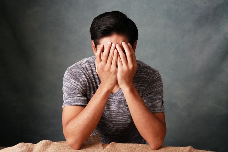 顔に手を当てる男性